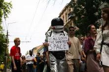 An Equality March participant wearing a space suit with a poster “We all look the same from space”