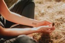 The participant is sitting on the grass, she has a tattoo on her arm "Be yourself"