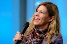 A blond woman smiling and speaking with microphone - Antonie 