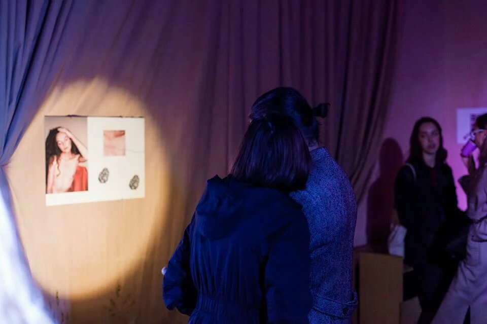 A young man and a young woman are looking at one of the works from the Pozor exhibition