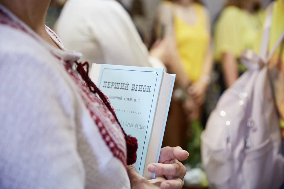 Жінка тримає в руках перевидання книги Перший вінок 