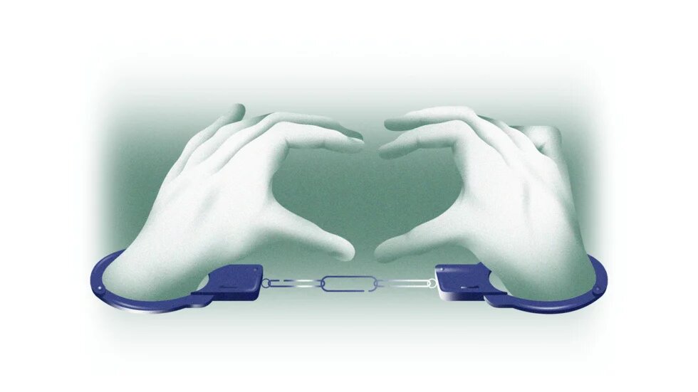 Руки полоненого в наручниках показують сереце 