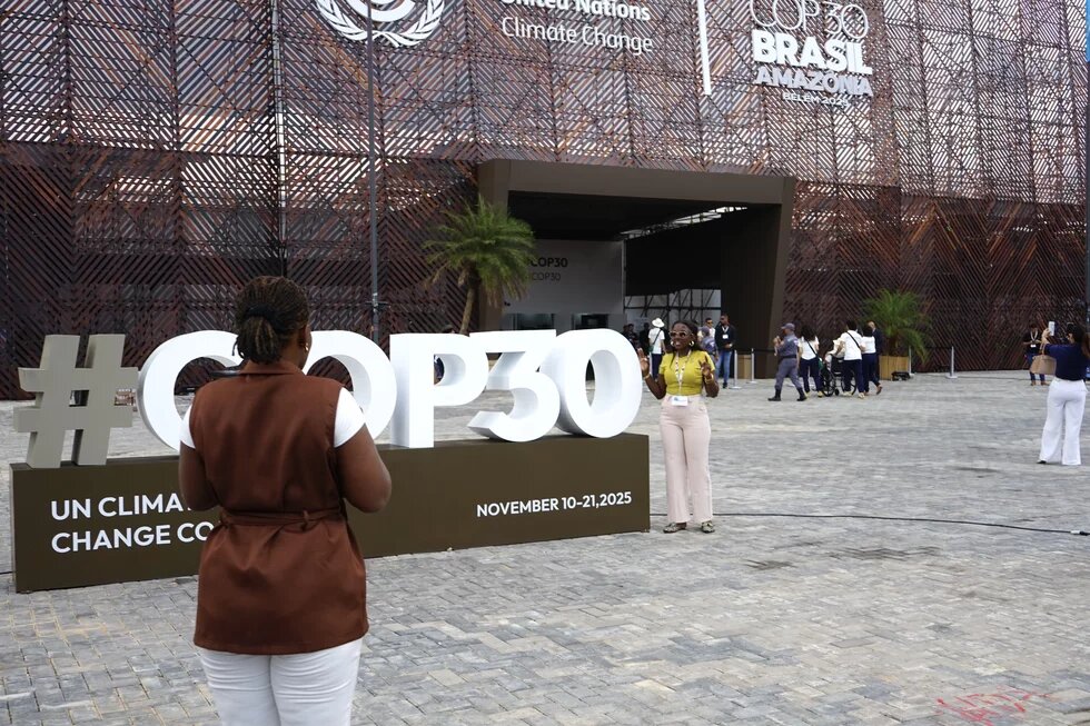 Жінки фотогафуються з великими літерами COP на церемонії відкриття події